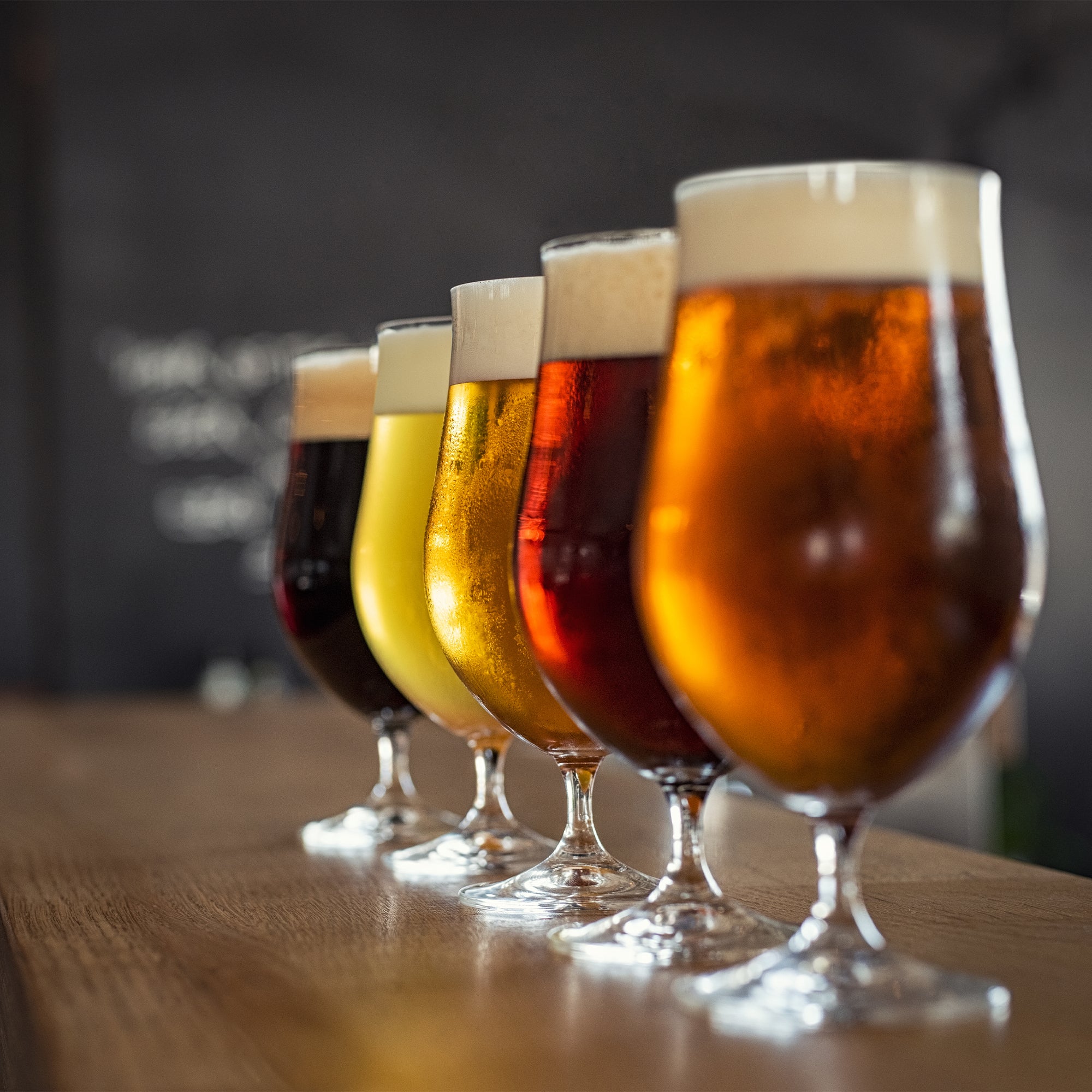 Different flavors of beer lined on a bar top with link to blog for hosting a beer tasting party